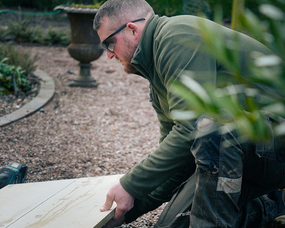 TMW employee cutting wood for bespoke pond build | TMW Pond Services